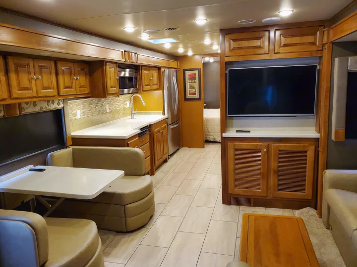 Spacious, modern RV rental interior with full kitchen, dining booth, and living room. Perfect for travel comfort.. Tiffin Motorhomes Allegro Open Road 2016