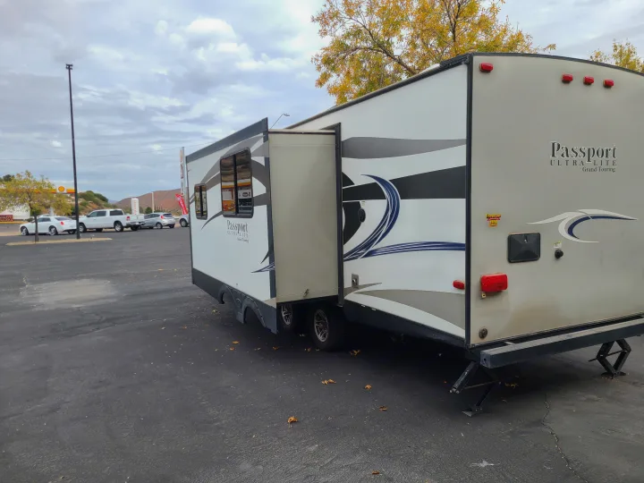 This RV rental, a Passport travel trailer with its slide-out extended, is parked in an outdoor lot under a cloudy sky.. Keystone Passport Ultra-lite Grand Touring 2016