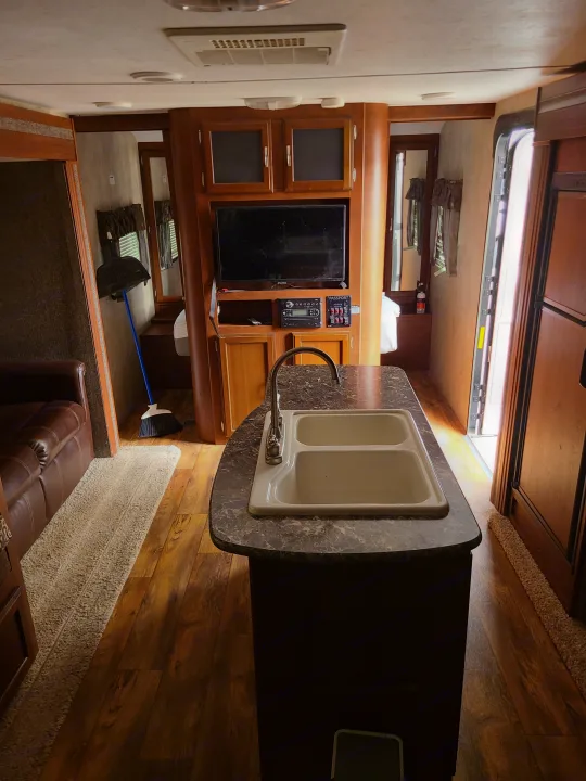 RV rental interior with a kitchen sink, entertainment center, sofa, and wood flooring, perfect for travel.. Keystone Passport Ultra-lite Grand Touring 2016