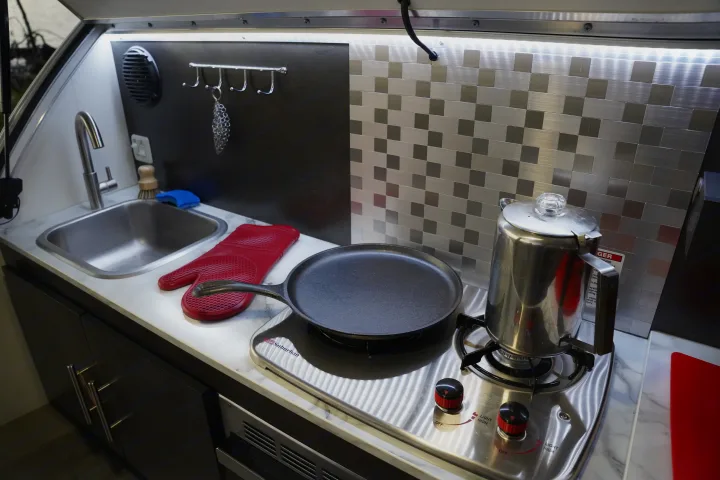 Enjoy home comforts in this RV rental's compact kitchen. Features a sink, stove, pan, and percolator.. nuCamp T@G 2021