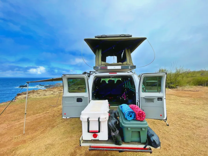 This RV rental, featuring a pop-top tent and pull-out gear, offers stunning ocean views for ultimate camping adventures.. Ford Econoline 2009