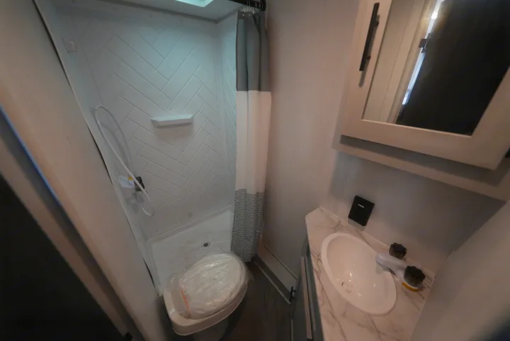 Inside an RV rental: a compact bathroom with a wet bath shower, protected toilet, and functional sink vanity.. Forest River Wildwood FSX 2022