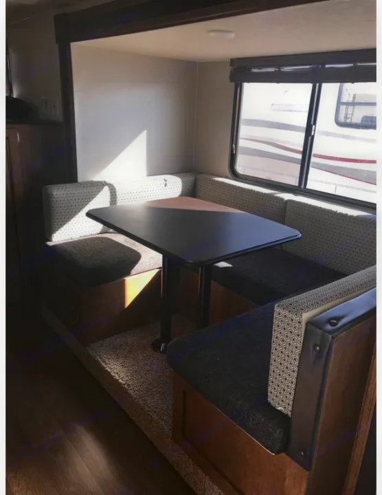 Bright RV rental dinette featuring a dark table & plush bench seating with a window view. Ideal for your journey.. Forest River Salem Cruise Lite 2018