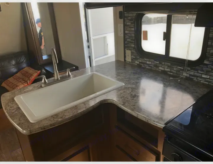 Inside this RV rental: a modern kitchen with large sink, counter, stovetop, and comfortable seating area.. Forest River Salem Cruise Lite 2018
