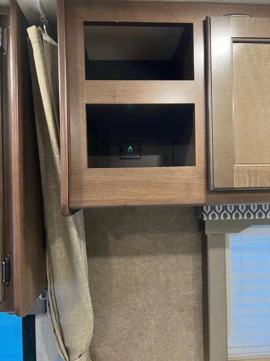 RV rental interior featuring wooden overhead cabinets with an open shelf, a USB charging port, a curtain, and window blinds.. Thor Freedom Elite 2020