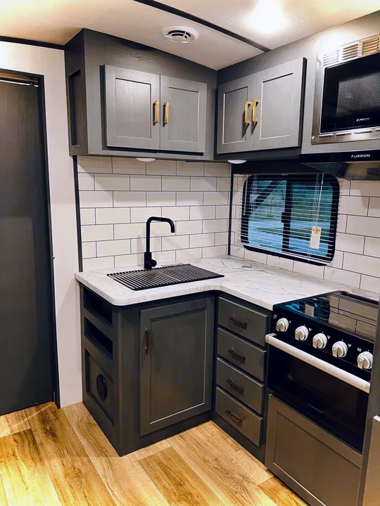 Modern RV rental kitchen with sleek grey cabinets, subway tile backsplash, marble-look counters, and full cooking amenities.. Keystone Bullet 250BHS 2022