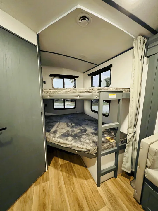 This RV rental features a bright interior with comfy bunk beds, small windows, and a ladder, perfect for family trips.. Keystone Bullet 250BHS 2022
