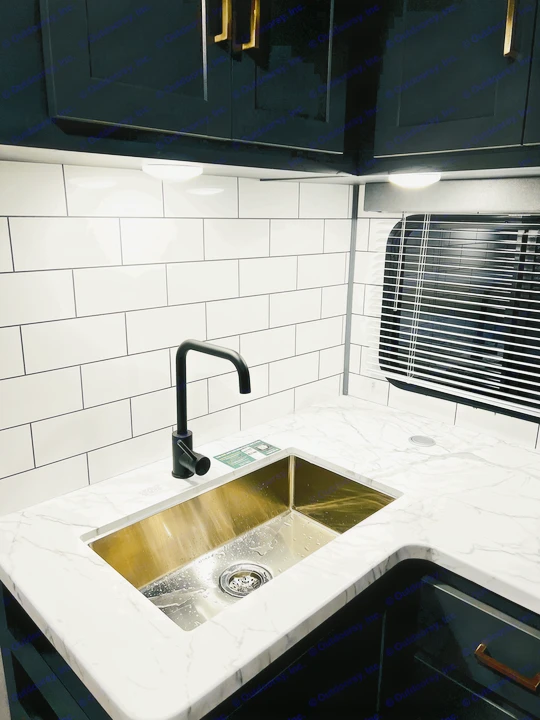 Modern RV rental kitchen: sleek black faucet, gold sink, white marble-look countertop, and subway tile backsplash.. Keystone Bullet 250BHS 2022