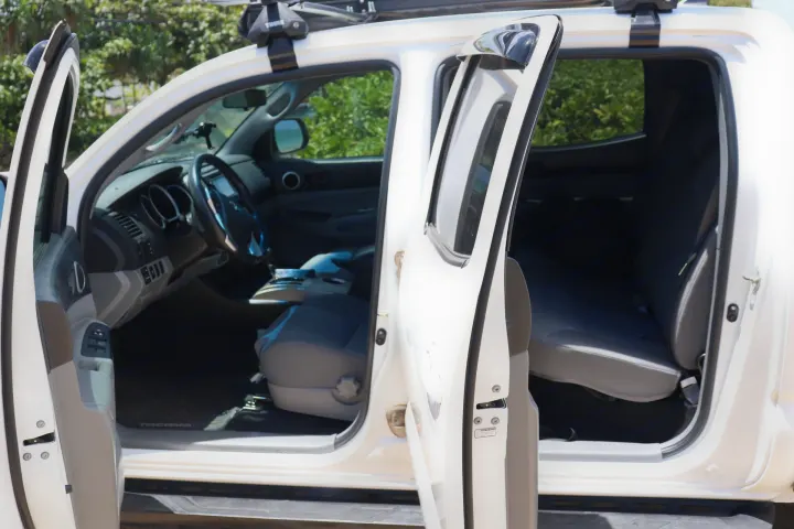 White pickup truck interior with open doors, showcasing spacious cabin and seating. Ideal for trips, complementing your RV rental adventure.. Toyota Tacoma 2015