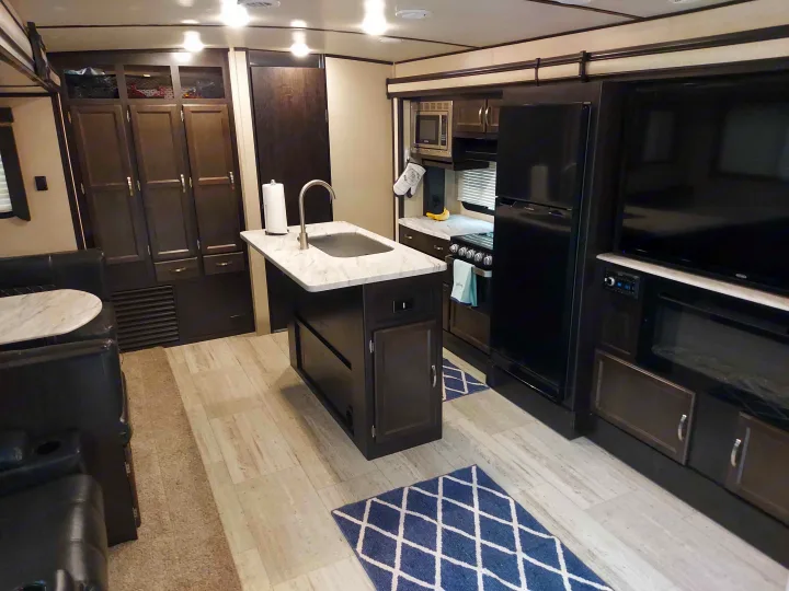Spacious RV rental interior. Features a modern kitchen island, dining booth, and entertainment area with TV.. Coachmen Other 2020