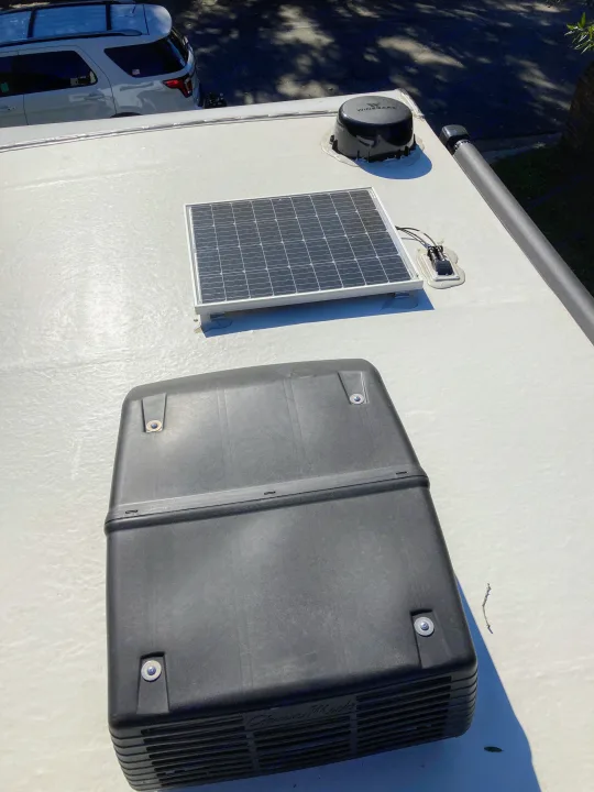 Overhead of an RV rental roof: solar panel, Winegard antenna, and large AC unit. Clear view of essential rooftop components.. Forest River Surveyor Legend 2022