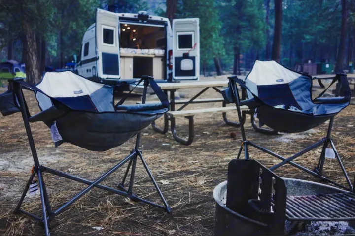 Relaxing at a forest campsite with an RV rental, two hammock chairs, a picnic table, and a fire pit.. Hymer Hymer Class B 2019