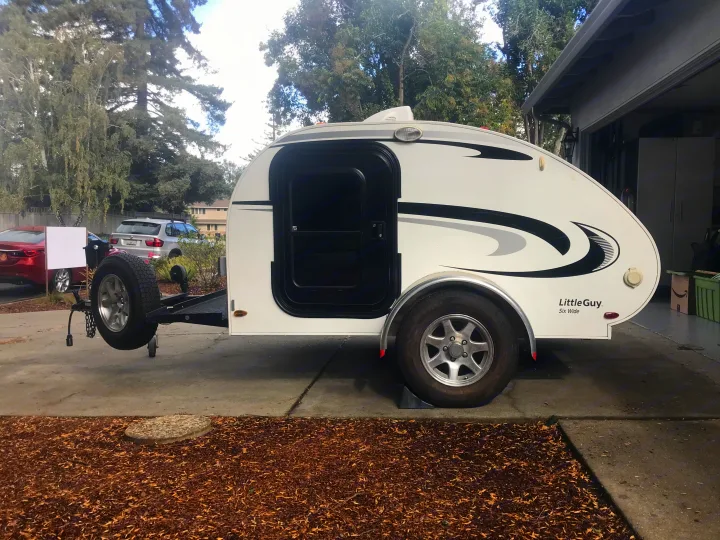 White Little Guy Six Wide teardrop camper, an RV rental option, parked on a paved driveway.. Little Guy Other 2011