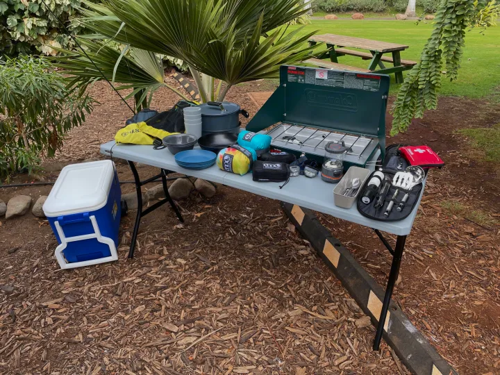 RV rental ready with essential camping gear: Coleman stove, cookware, cooler, and lights set up on a table for outdoor cooking fun.. Jeep Wrangler 2017