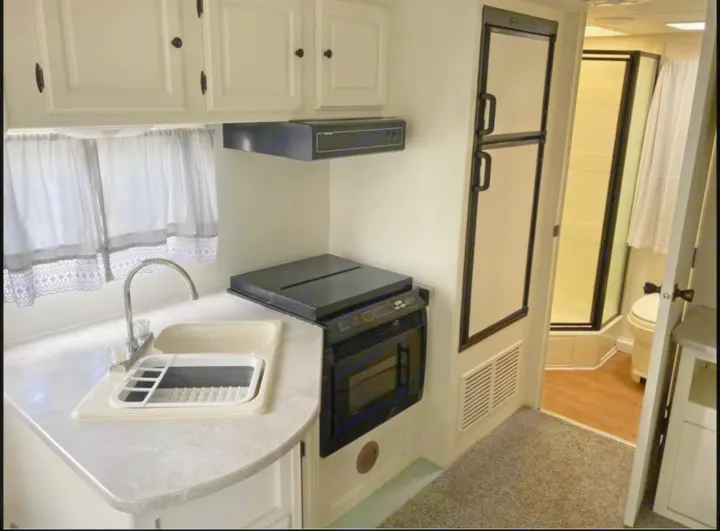 RV rental featuring a compact kitchen with sink, microwave, and cabinets, plus a bathroom with toilet and shower.. Heartland North Trail 2009