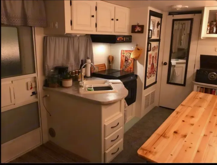 This inviting RV rental features a well-appointed kitchen with a sink, stove, and a large wooden dining table.. Heartland North Trail 2009