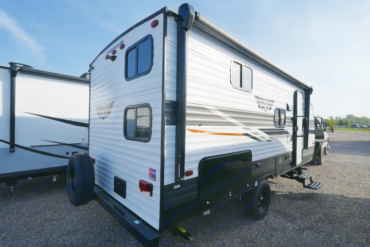 Modern travel trailer, perfect for your next RV rental adventure. White RV with sleek graphics parked on a sunny gravel lot.. Wildwood FSX 178BHsk 2022