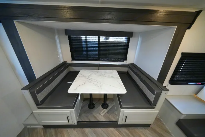 Spacious RV rental dinette with comfortable gray bench seating and a white marble-look table, perfect for meals in your travel trailer.. Wildwood FSX 178BHsk 2022