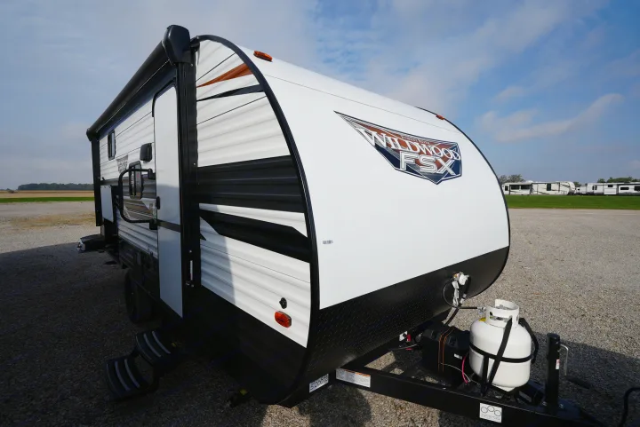 White Wildwood FSX travel trailer, perfect for an RV rental. Features include an awning, steps, and front propane tank on gravel.. Wildwood FSX 178BHSK 2022