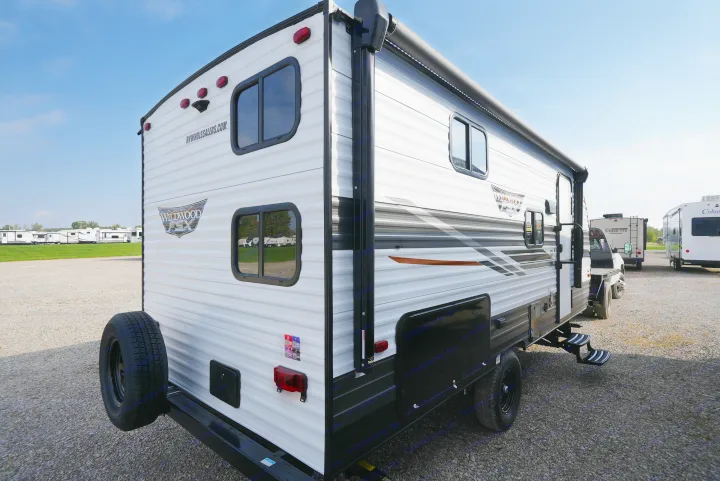 A white and black Wildwood FSX travel trailer, perfect for RV rental adventures, parked on a sunny gravel lot.. Wildwood FSX 178BHSK 2022