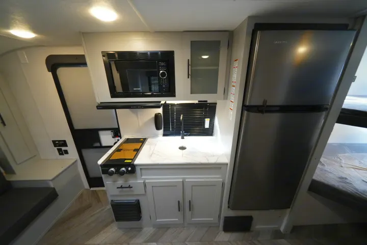 Compact RV rental kitchen with a microwave, stovetop, sink, and refrigerator, maximizing space for travelers.. Wildwood FSX 178BHSK 2022