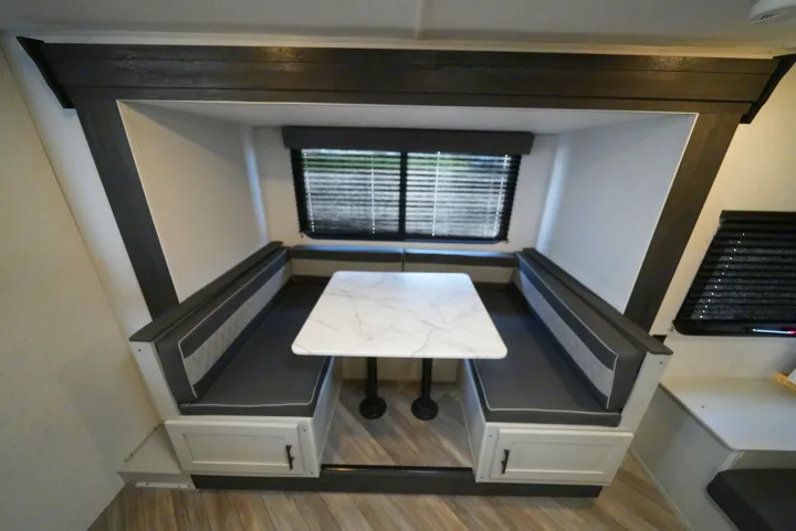 RV rental: Spacious modern dinette with a white tabletop, gray cushioned U-shaped booth seating, and under-seat storage.. Wildwood FSX 178BHSK 2022