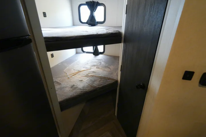 Cozy RV rental bunk beds with windows, providing comfortable sleeping arrangements inside a travel trailer.. Wildwood FSX 178BHSK 2022