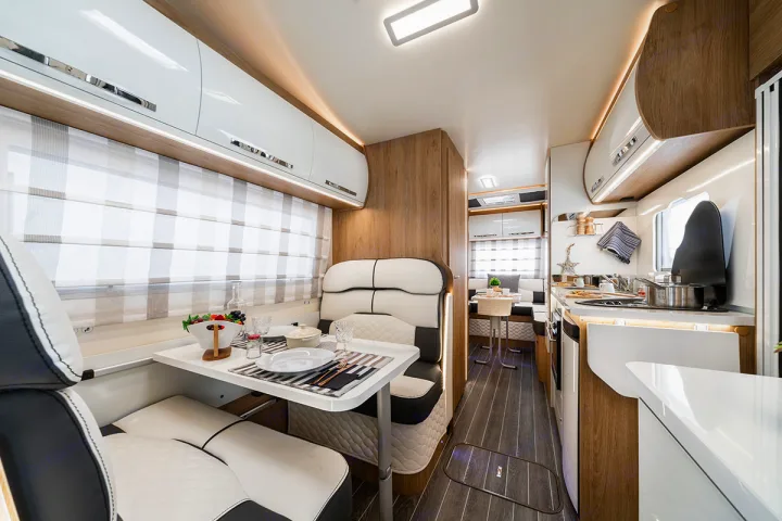 rv rental: A modern and well-lit RV interior, featuring a dining area with black and white seating, and a compact, functional kitchen.. Ford Rollerteam 747 2026