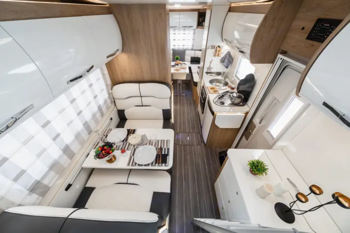Spacious rv rental interior featuring a modern kitchen with stovetop, dining area with table for two, and sleek storage.. Ford Rollerteam 747 2026