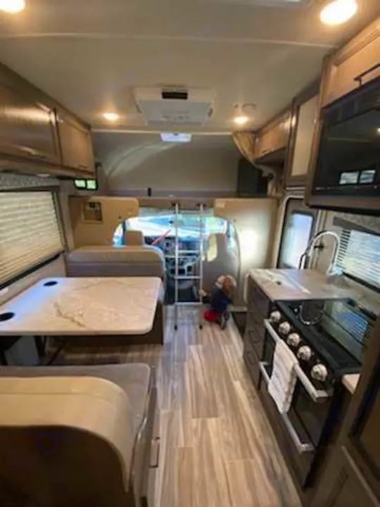 Spacious RV rental interior with kitchen, dining area, and a child near the bunk ladder.. Thor Freedom Elite 2021