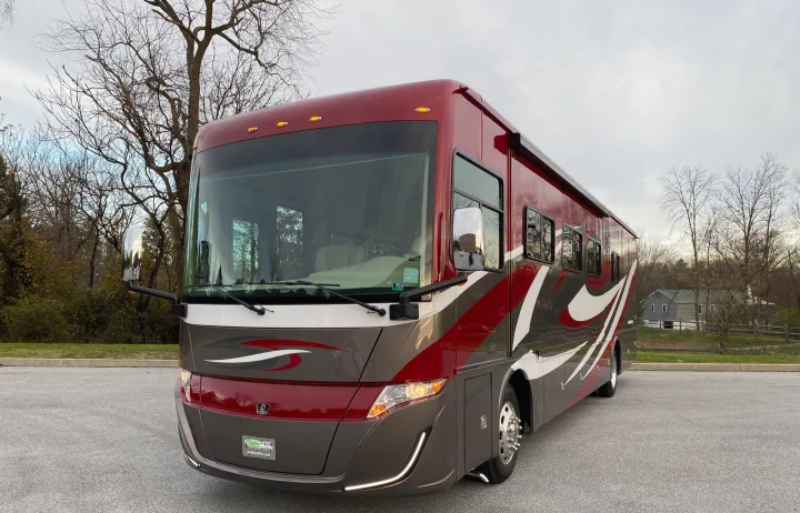 Spacious red & grey luxury motorhome, ready for rv rental. Parked outdoors with bare trees in the background, ideal for travel.. Tiffin Motorhomes Allegro Red 2021