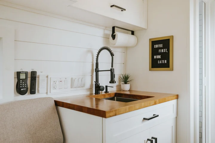 RV rental: Modern kitchenette with black faucet, wood counter, smart controls, and "Coffee First" sign for compact living.. Ram Promaster 2500 2021