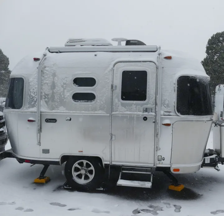 Snow-covered silver Airstream travel trailer, ideal for a cozy winter rv rental getaway.. Airstream Caravel 2020