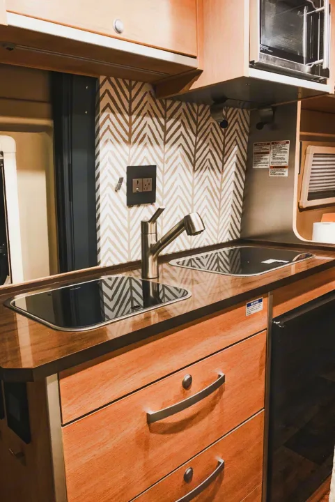 This RV rental features a sleek, compact kitchen with a modern backsplash, integrated cooktop/sink, and microwave.. Hymer Hymer Class B 2019