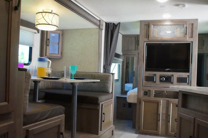 Bright RV rental living space with dining, kitchenette, TV, and bedroom glimpse. Ideal for trips.. Apex Nano 245 BHS 2020