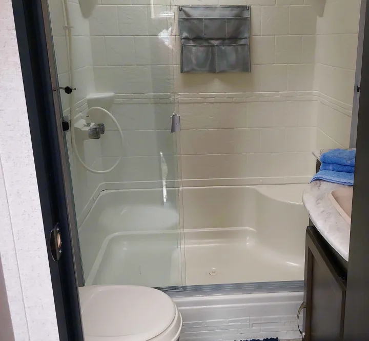 RV rental bathroom: white shower/tub with glass doors, toilet, and vanity with blue towels.. Coachmen Other 2020