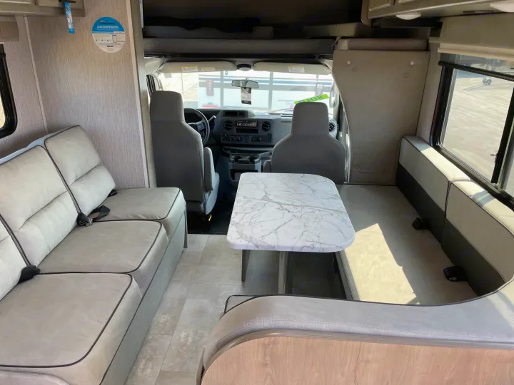 Inside a bright rv rental, featuring a marble-look dinette, comfortable grey seating, and front cockpit area.. Forest River Coachmen Freelander 2021