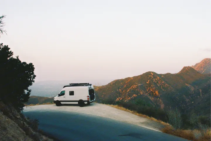White camper van (RV rental) parked on a mountain overlook, offering stunning views of valleys and distant peaks. Ideal road trip!. Mercedes-Benz Sprinter 2017