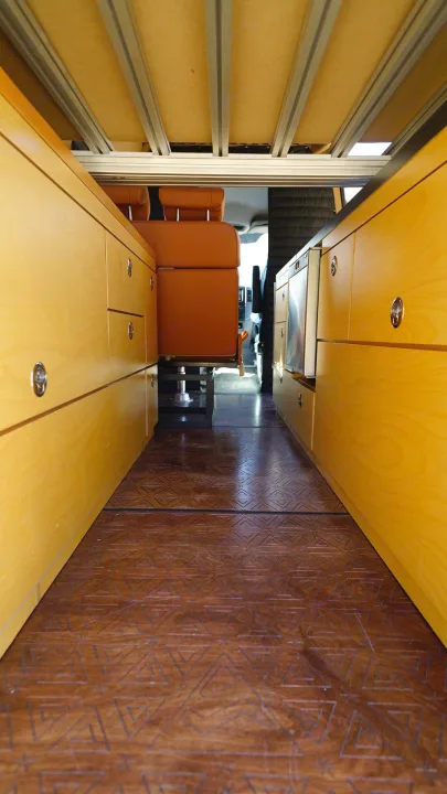 RV rental interior: distinctive patterned wood wall, bright overhead and lower cabinets, and orange passenger seating.. Mercedes-Benz Sprinter 2017