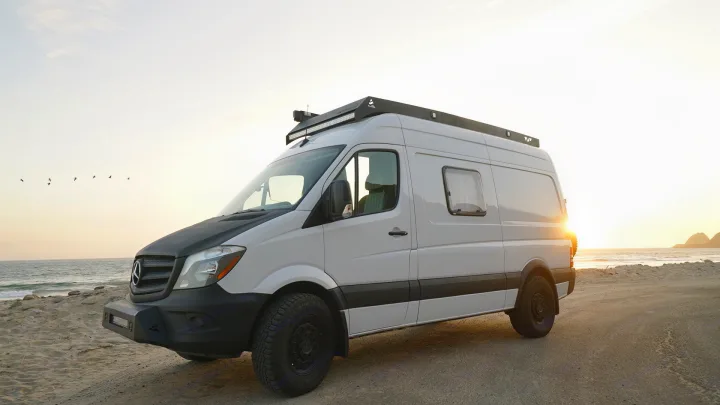 White Mercedes Sprinter camper van parked on a beach at sunset, perfect for an RV rental adventure.. Mercedes-Benz Sprinter 2017