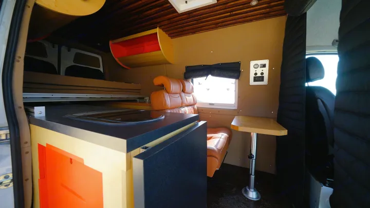 Experience comfort in this RV rental's interior: modern kitchenette, raised bed, and bright living space with seating.. Mercedes-Benz Sprinter 2017