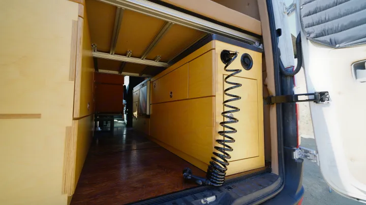RV rental: Camper van's wood interior features custom storage cabinets, rugged flooring, and a rear utility/shower system.. Mercedes-Benz Sprinter 2017