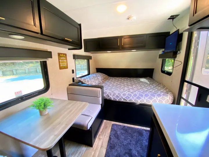 Comfortable RV rental interior showcasing a cozy bed, dinette, and sleek overhead cabinets. Perfect for trips!. Forest River Wolf Pup -Black Label 2021