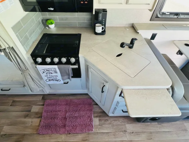 A well-equipped RV rental kitchen featuring a stove, sink, coffee maker, and practical extendable counter space.. Jayco Alante 2021