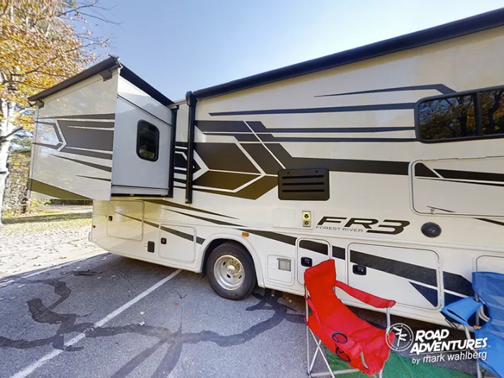 Parked RV rental: A white Forest River FR3 motorhome with extended slide-out and camping chairs.. Forest River Fr3 2021