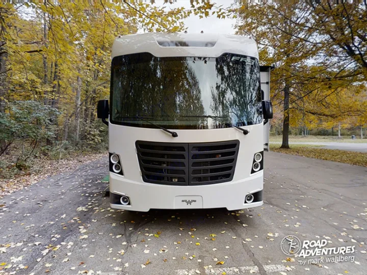 Front view of a white RV rental, a modern motorhome, parked under golden autumn trees.. Forest River Fr3 2021