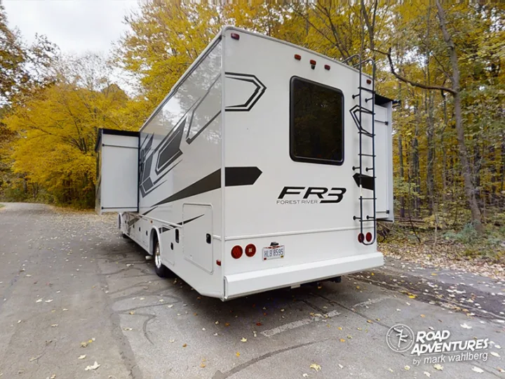 This white Class A RV rental, a Forest River FR3, is parked with its slide-out extended in an autumn forest.. Forest River Fr3 2021