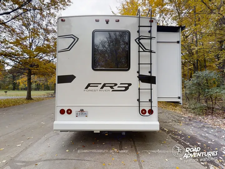 Rear view of a white FR3 rv rental with slide-out extended in an autumn campsite, ready for your road trip.. Forest River Fr3 2021