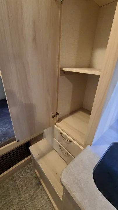 RV rental interior: Light wood cabinetry with open shelving, two drawers, and a bunk area for compact living.. Winnebago Hike 2022