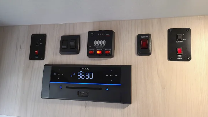 RV rental interior: control panel with tank levels & water heater, awning & slide-out switches, plus Connex stereo (96.90 FM).. Winnebago Hike 2022